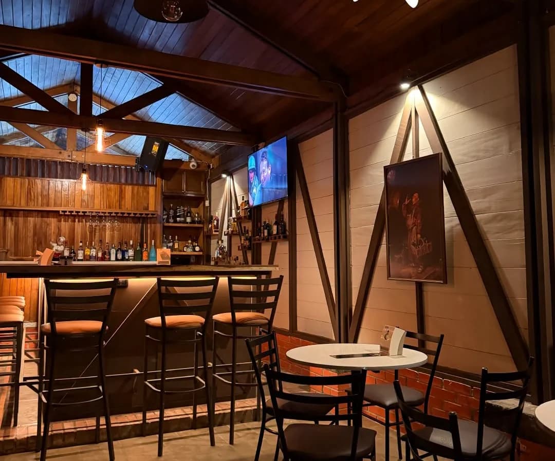 Salón de Marlon Restaurante: barra de madera, mesas y techo de viga a la vista.