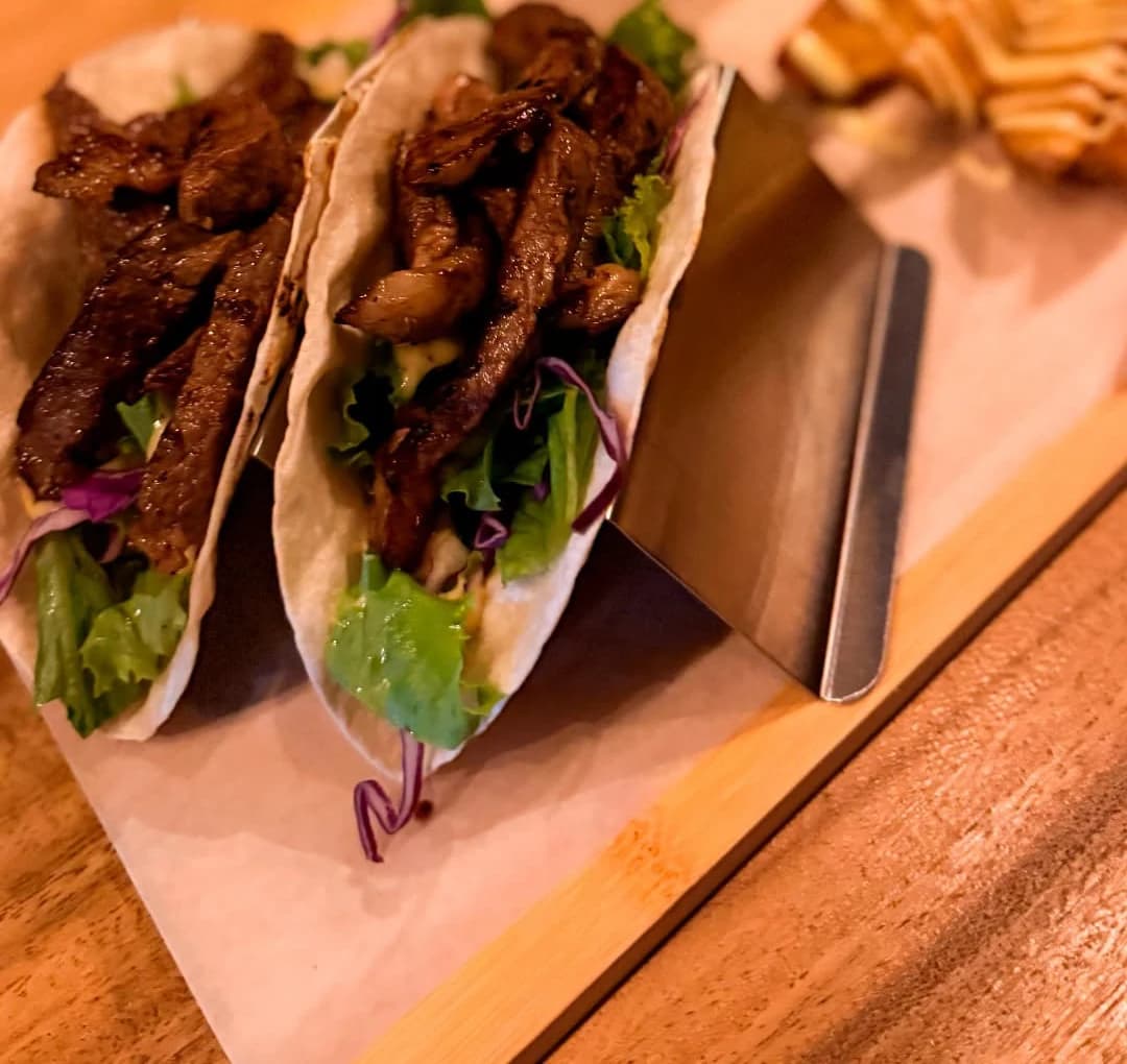 Tacos de picaña de Marlon Restaurante, en tabla de madera con guacamole y papas.